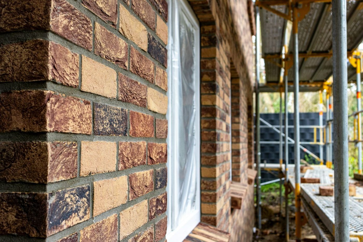 Facing brickwork rising beside scaffolding